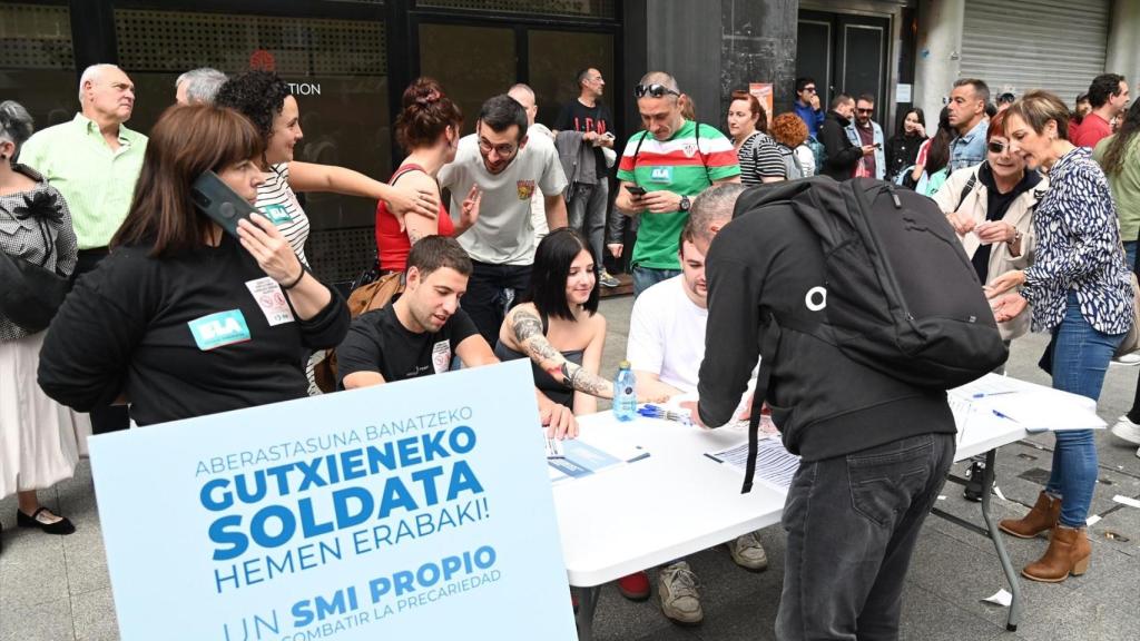 Varias personas firman por un SMI vasco durante la manifestación por el Día del Trabajador