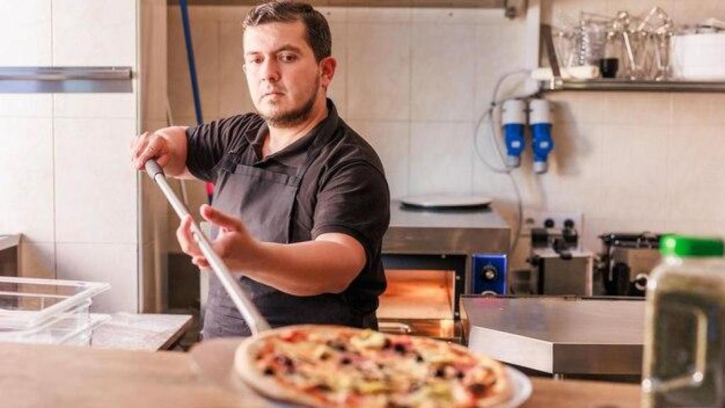 Un hombre elabora una pizza.