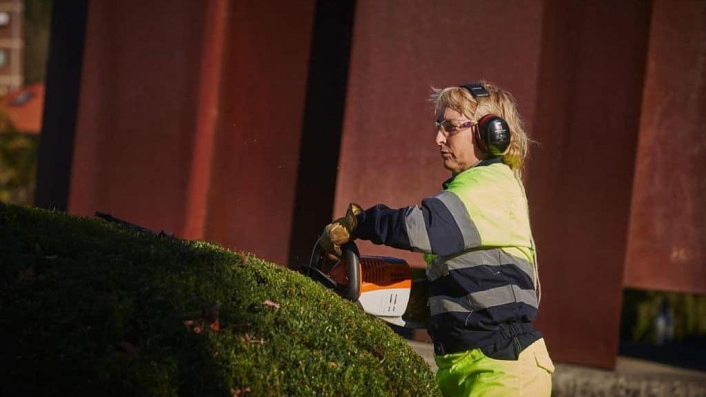 Una trabajadora de Enviser desbroza un seto