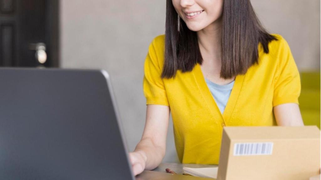Mujer con un paquete frente a un ordenador portátil