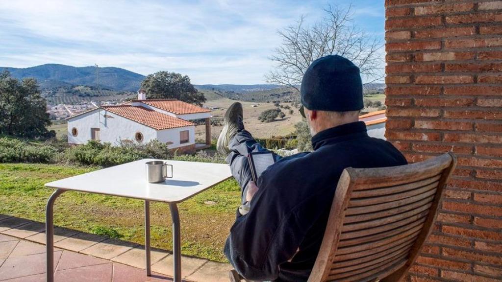 Un usuario de un alojamiento rural descansa en el porche de la casa