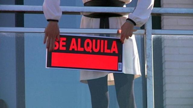 Una persona coloca en un balcón el cartel de se alquila