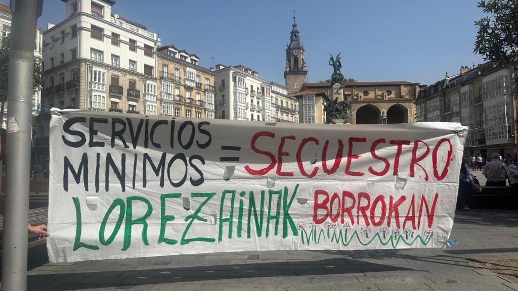 Pancarta colocada este martes frente a la carpa de la Plaza de la Virgen Blanca para denunciar los servicios mínimos solicitados por el Ayuntamiento de Vitoria y aceptados por el Gobierno vasco