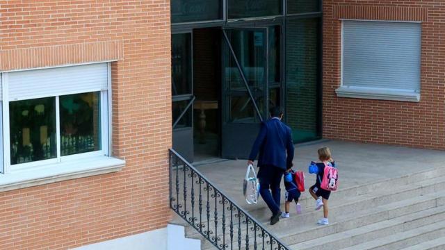 Un padre acompaña a sus hijos a la entrada de un colegio
