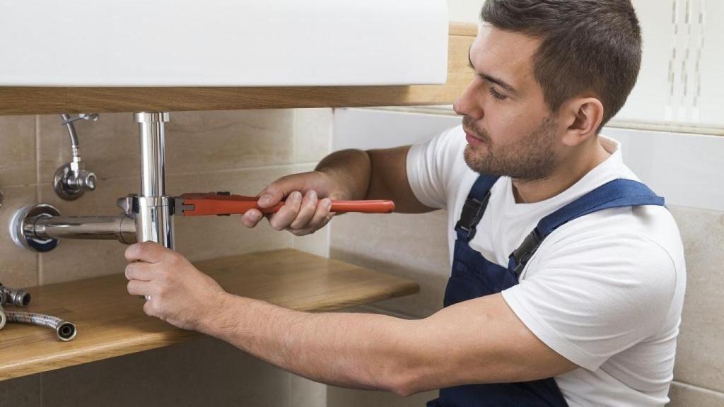 Un fontanero arreglando el lavabo.