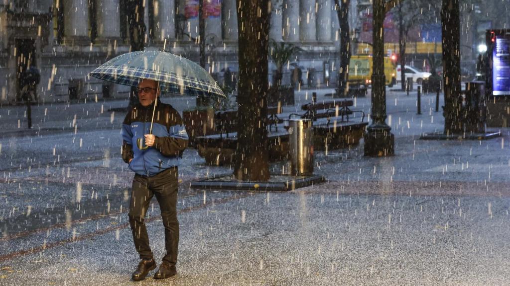 Un hombre se protege de una intensa granizada caída este viernes en el centro de Bilbao.