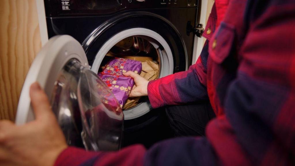 Una persona esconde un regalo en una lavadora