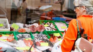 Una señora mira los productos y los precios de una pescadería en una imagen de archivo