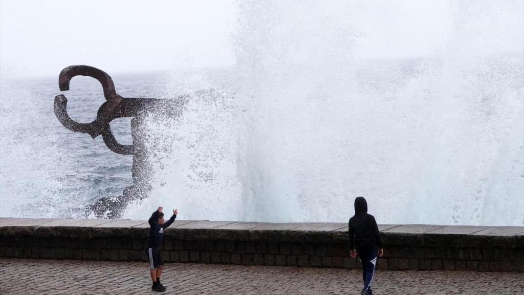 Varias personas se mojan con las olas en el Peine del Viento, en San Sebastián, en una imagen de archivo