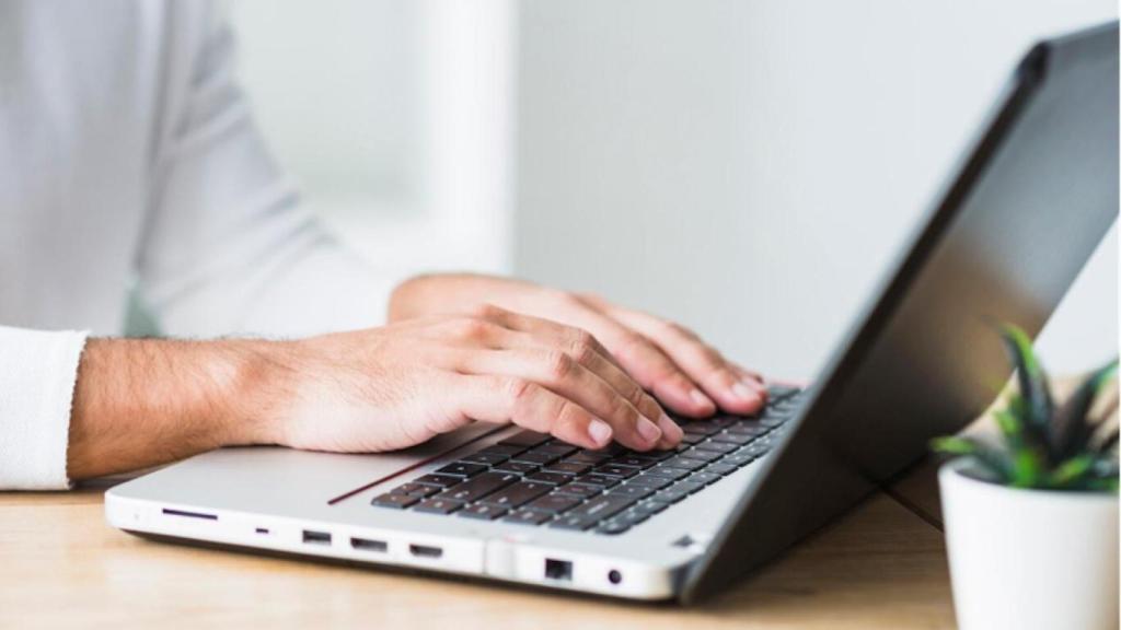 Hombre teclea sobre un ordenador portátil