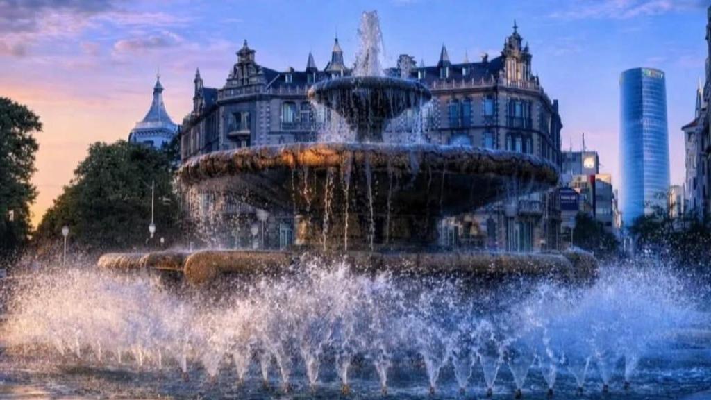 La Plaza fue diseñada en 1940 por José Luis Salinas y remodelada a finales de siglo por su hijo. La fuente fue desmontada y custodiada durante los tres años que duraron los trabajos de restauración llevados a cabo ante la llegada del metro. Norman Foster diseñó los fosteritos que abocan en la plaza. En una de las calles que la atraviesan, Alameda Recalde, se encuentra la peculiar Casa Montero, conocida como casa Gaudí, aunque el catalán no fuera su arquitecto