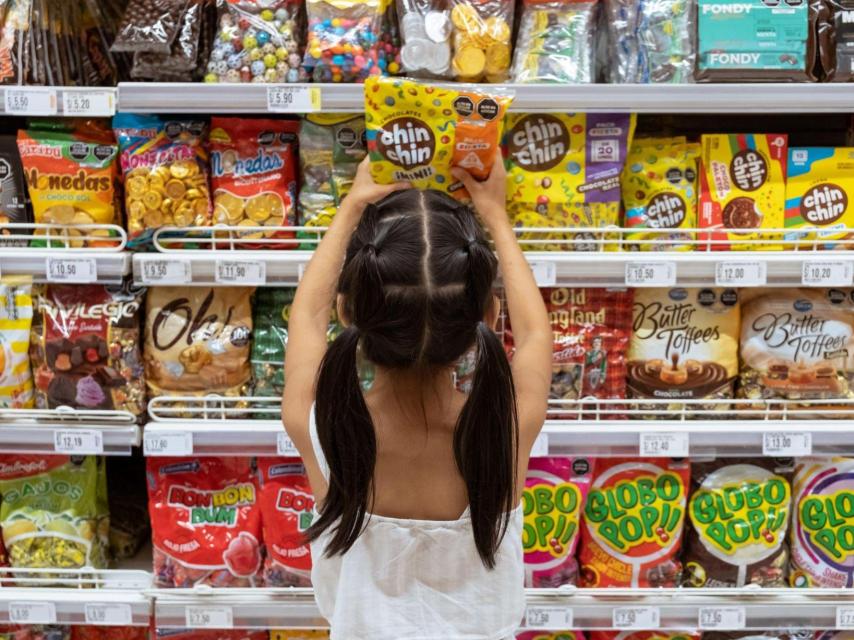 Una niña ante un aparador de chuches y golosinas