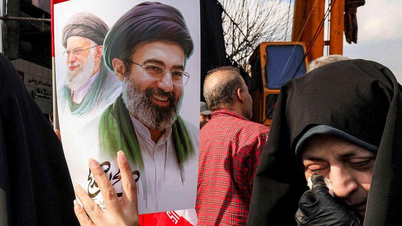 Una mujer sostiene las imágenes de los dos ayatolás Jamenei en Irán.