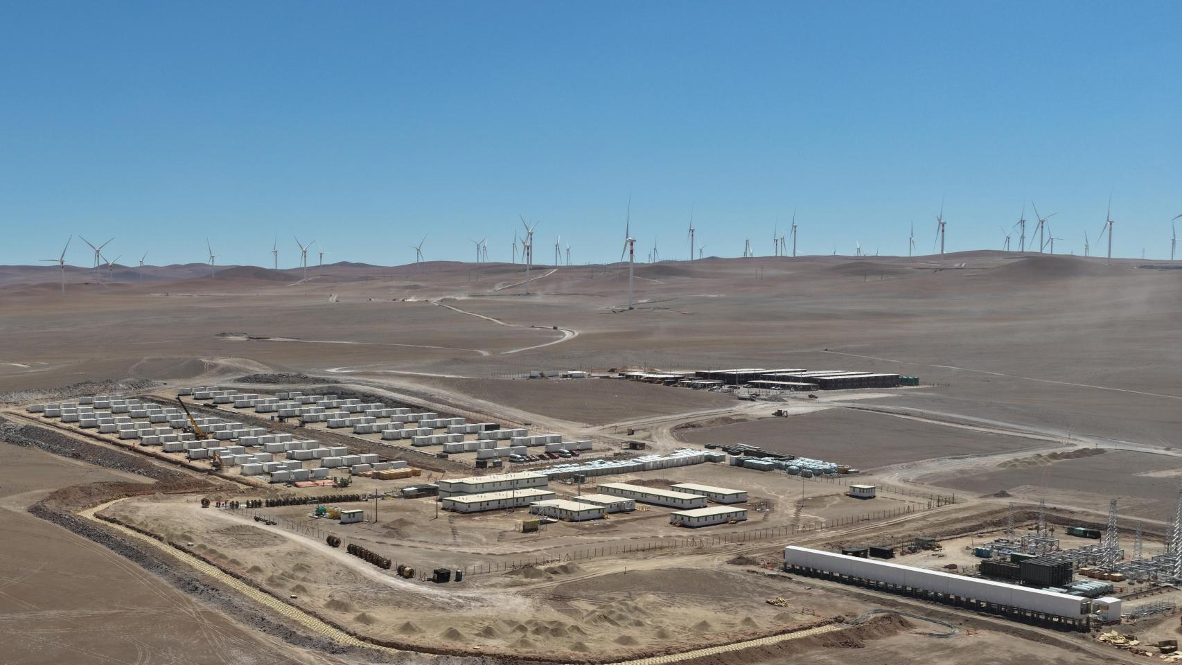 Un proyecto híbrido de GES en Chile en el que se observa la instalación BESS y la subestación eléctrica con un parque eólico al fondo