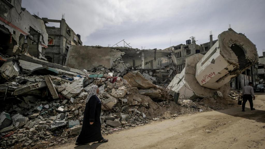 Una mujer palestina camina frente a un lugar destruido por un ataque aéreo de Israel, en una fotografía de archivo