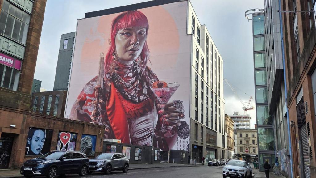 Keeper of light. Menos de un mes tardó Smug One en realizar este mural hiperrealista, al que puso punto y final el pasado mes de agosto. En él una joven asiática perteneciente al colectivo LGTBI porta una vela como guiño a la zona de Candleriggs, donde se encuentra ubicado. Además esconde en su vestimenta distinta simbología como el unicornio, animal nacional de Escocia; un anillo con la letra G en recuerdo de los edificios que ocupaban el lugar o un cóctel ,representando la modernidad