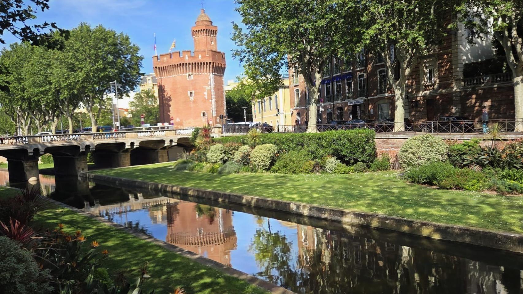 El clima suave del que todo el año disfruta Perpiñán y la luminosidad de la ciudad permiten tomar imágenes como esta en la que el Castillet se refleja sobre las aguas del Canal de la Bassa, un afluente del río Têt