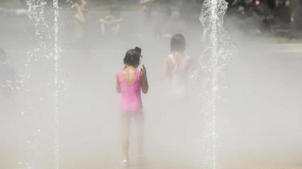 Varios niños se refrescan en una fuente en Bilbao en un día de calor