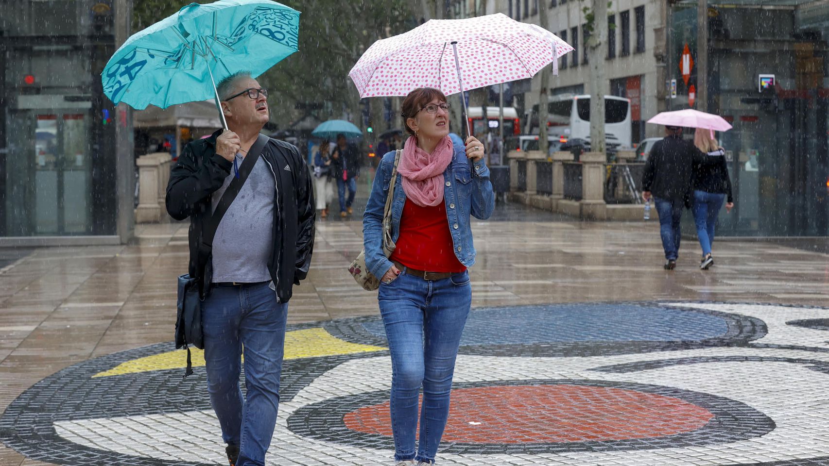 Varias personas se protegen de la lluvia mientras caminan por las Ramblas de Barcelona