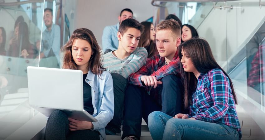 Un grupo de adolescentes miran la pantalla de un ordenador.