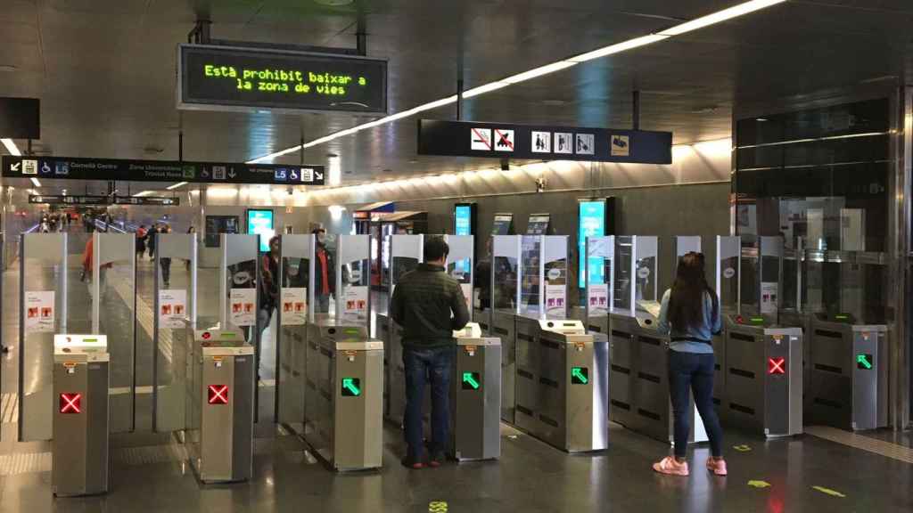 Usuarios en la estación de metro de Diagonal pasan sus tarjetas para poder acceder a las vías