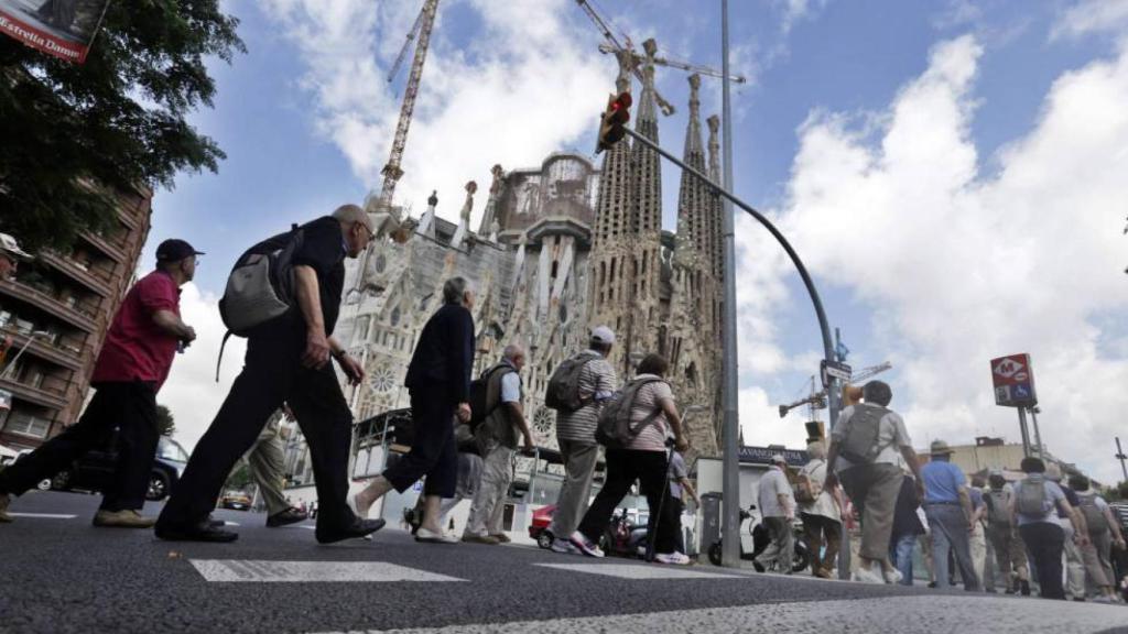 Un grupo de personas cruza una calle aledaña a la Sagrada Familia en Barcelona