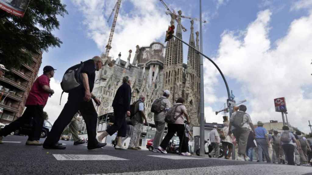 Un grupo de personas cruza una calle aledaña a la Sagrada Familia en Barcelona