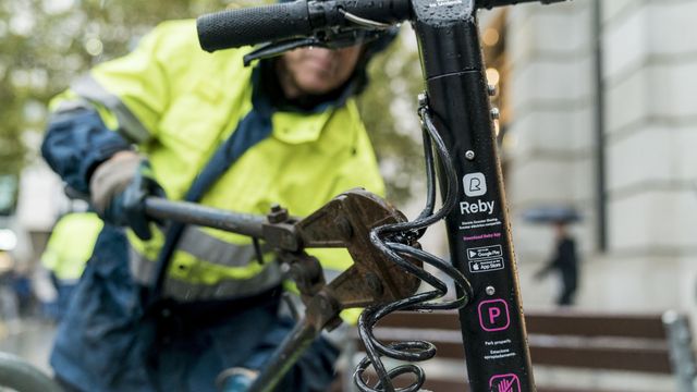 Un operario municipal corta la cadena de un patinete mal estacionado