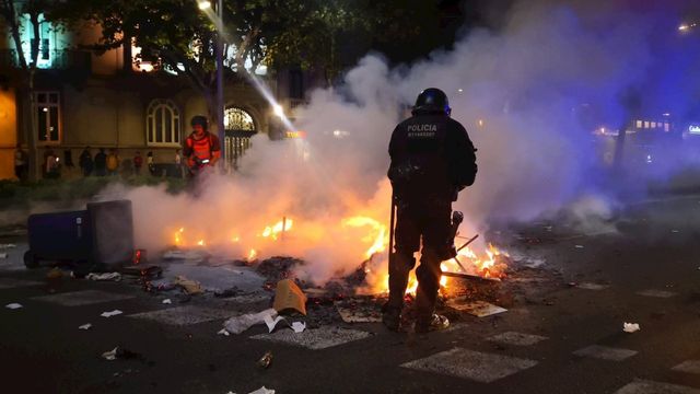 Un policía y un bombero al lado de un incendio generado durante la manifestación / EP