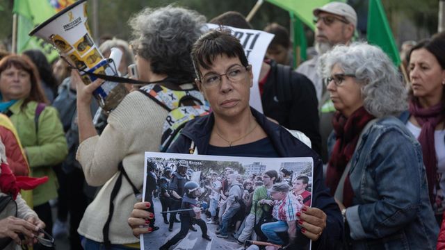Una mujer exhibe una imagen de las cargas en la manifestación que ha reunido a 4.000 personas  / EUROPA PRESS