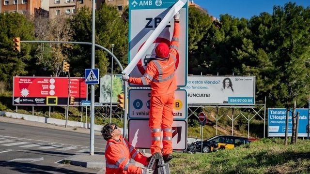 Unos operarios instalan unas señales de la ZBE / AMB
