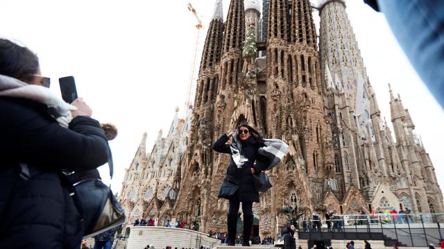 Turistas se fotografían ante la Sagrada Familia en un día de fuerte viento en Barcelona