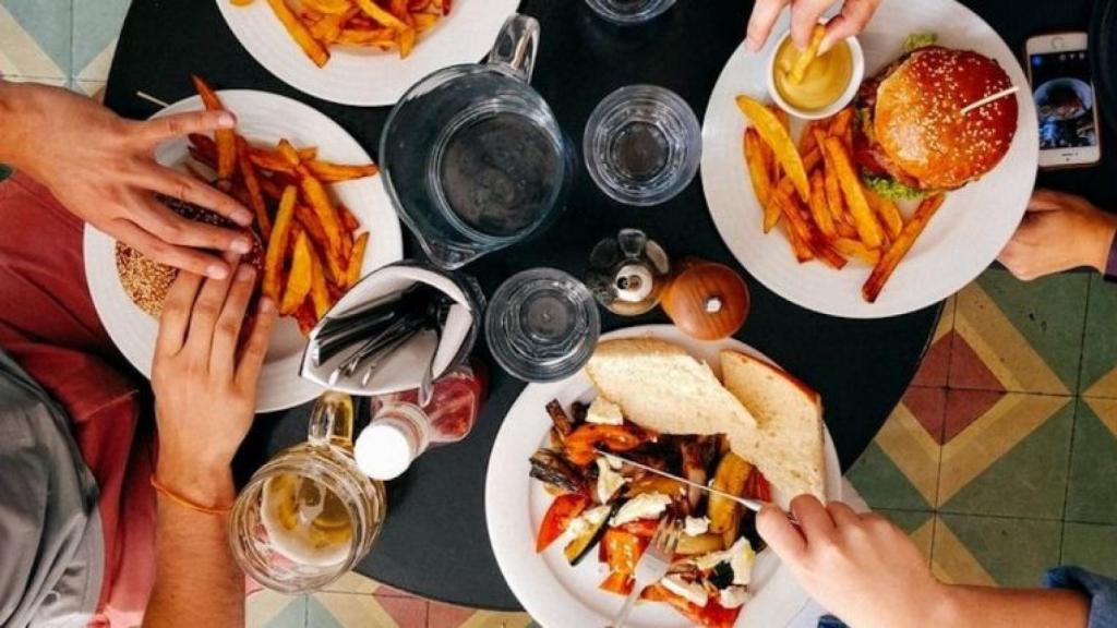 Cuatro comensales en un restaurante compartiendo una comida