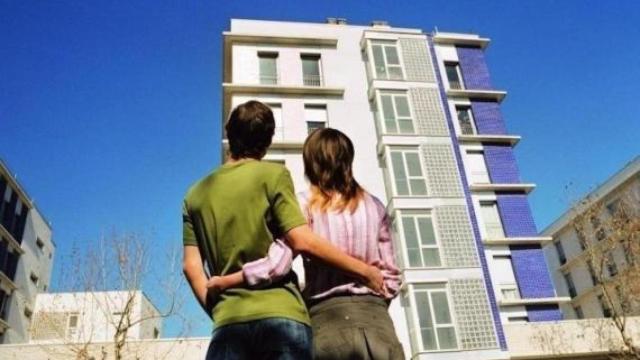 Una pareja joven frente a unas viviendas de nueva construcción