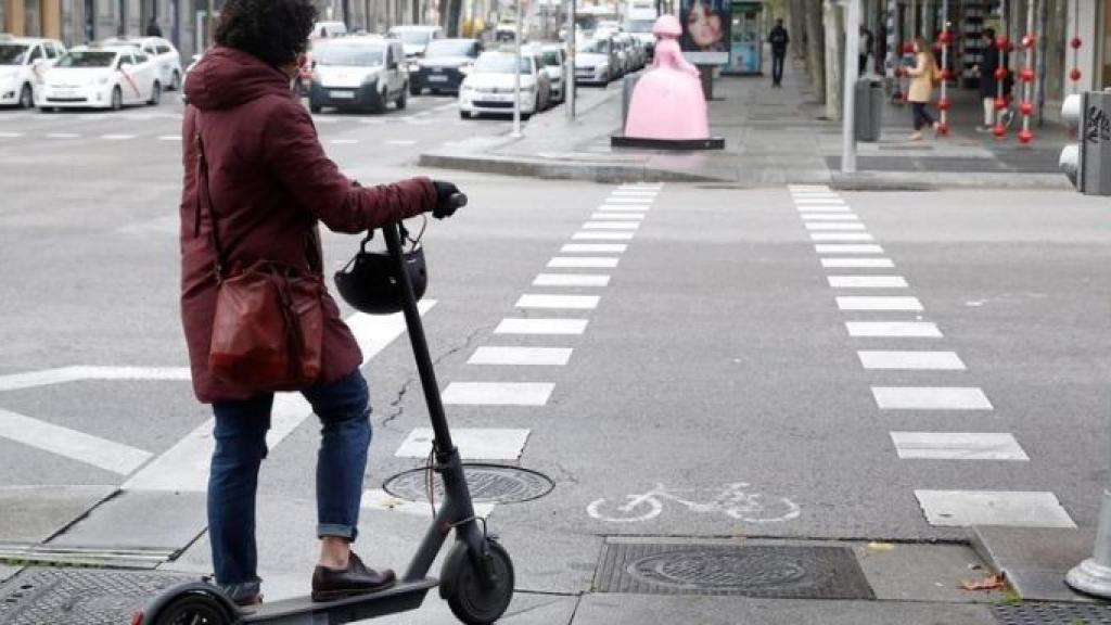 Una usuaria sin casco montada en un patinete eléctrico en Barcelona / EFE