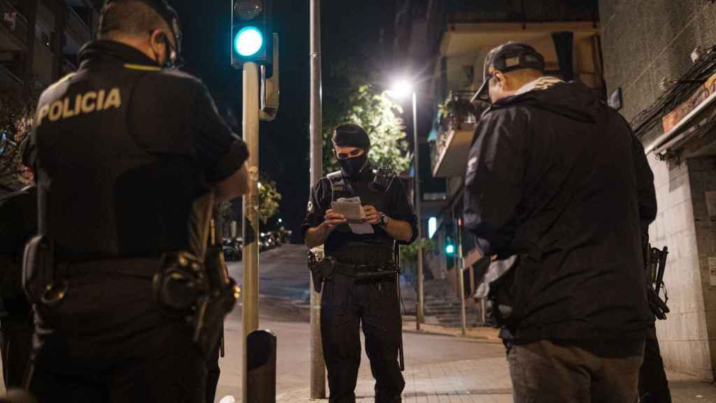 Agentes de la Omega, unidad antidisturbios, identifican a dos hombres que incumplían el toque de queda nocturno en Badalona