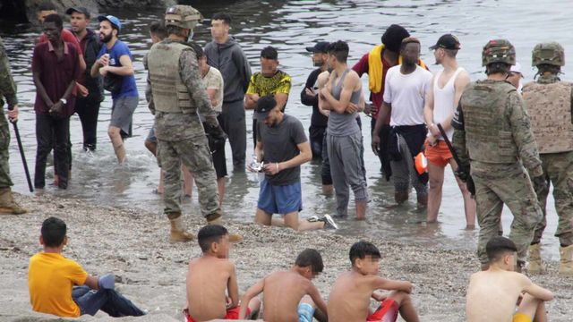 Miembros del Ejército de Tierra vigilan a un grupo de menores extranjeros no acompañados (menas) tras cruzar uno de los espigones fronterizos de Ceuta este martes / EFE - REDUAN