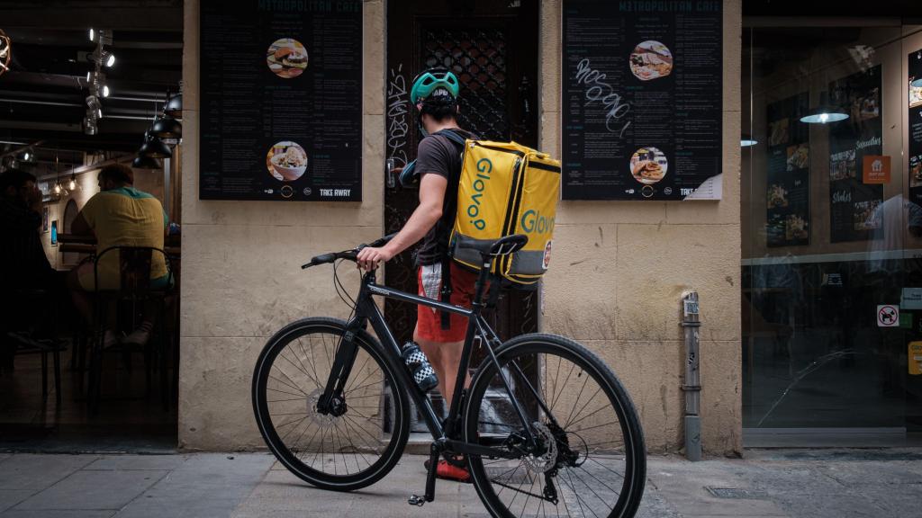 Un trabajador de Glovo esperando frente a un local en Barcelona