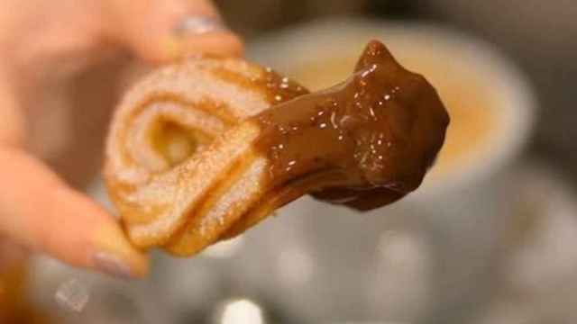 Un churro mojado en chocolate a la taza
