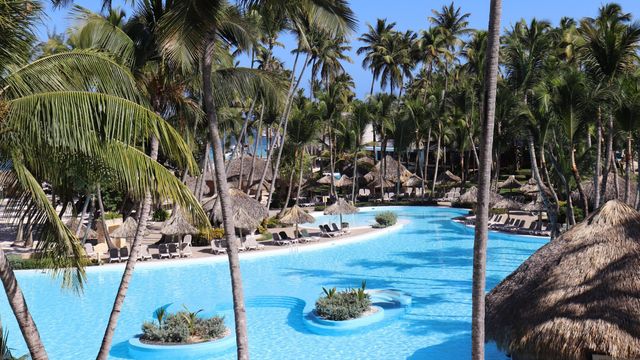 Hotel ubicado en Punta Cana con una piscina y múltiples palmeras
