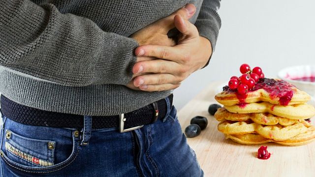 Un hombre se queja de dolor de estómago, uno de los síntomas del síndrome de intestino irritable / QUIRÓNSALUD