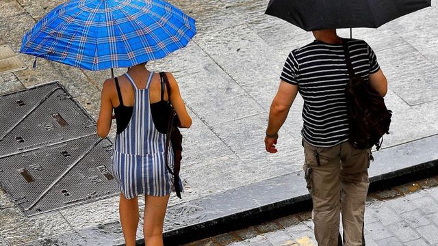 Dos personas se protegen de la lluvia de verano en Barcelona / EFE