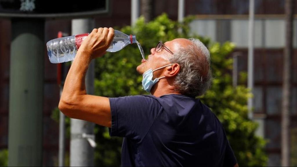 Un home beu aigua en plena onada de calor / EFE