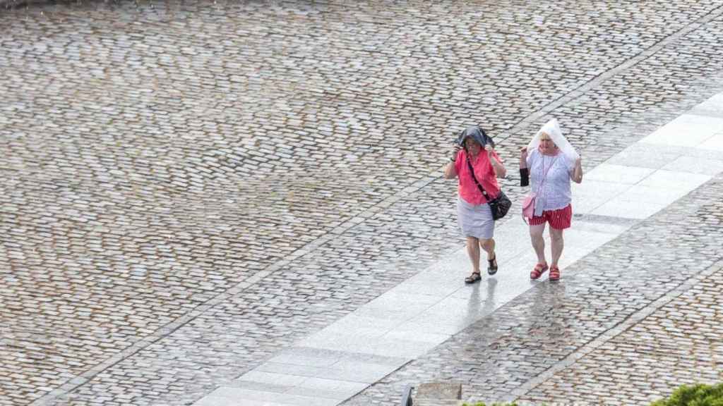 Dos mujeres se protegen de una lluvia de verano