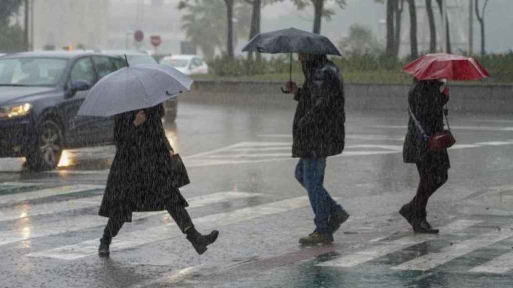 Diverses persones es cobreixen de la pluja amb paraigües en una imatge d'arxiu
