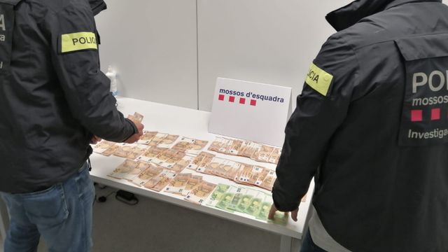 Agentes de los Mossos con el dinero incautado de la detenida por estafa / MOSSOS D'ESQUADRA