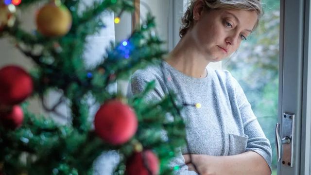 Una mujer pensativa junto a un árbol de Navidad / QUIRÓNSALUD