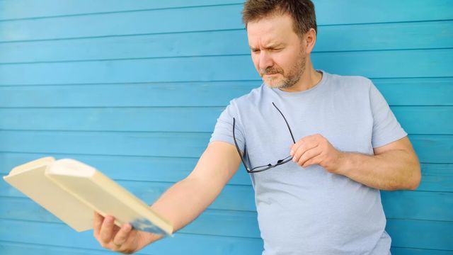 Un hombre aleja un libro para tratar de enfocar mejor: Un claro síntoma de la presbicia / CEDIDA QUIRÓNSALUD