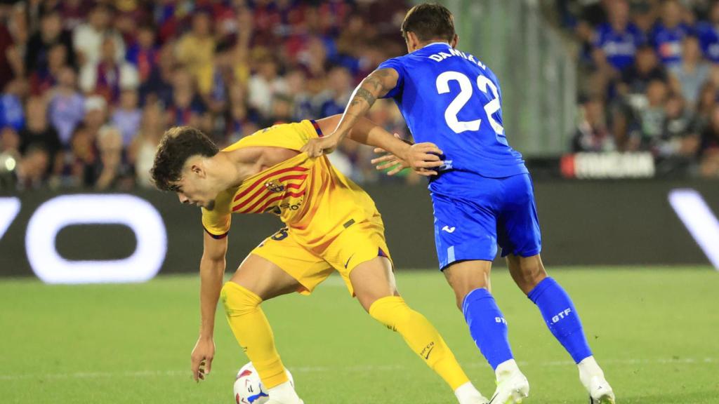 Ez Abde intenta controlar un balón, agarrado de la camiseta por Damián Suárez