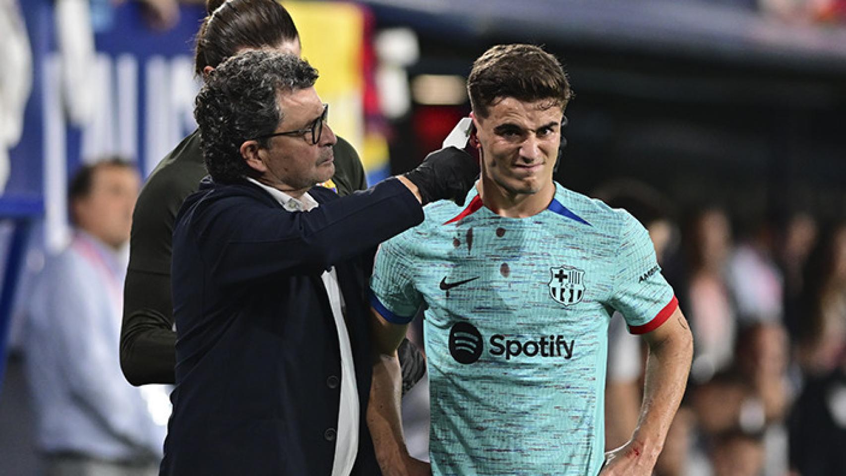 Gavi, atendido por Ricard Pruna, tras sufrir un duro golpe en la oreja derecha